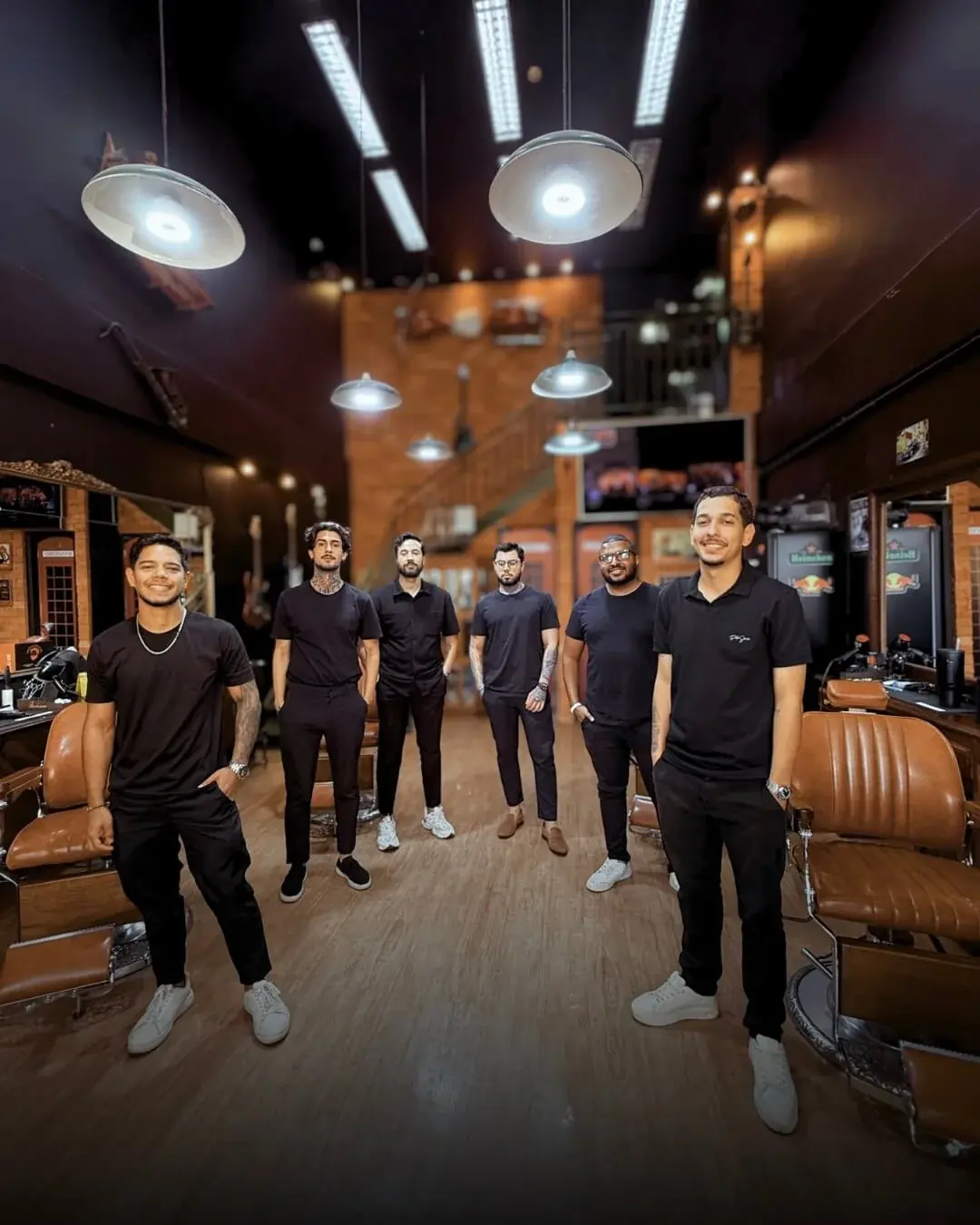 Equipe da Don Retrô em pé no salão, com as cadeiras de couro e as luminárias ao fundo