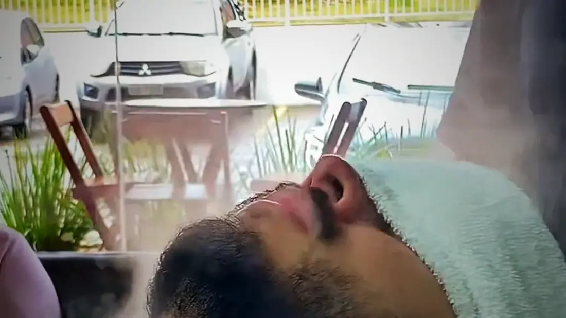 Cliente deitado com toalha quente no rosto durante o tratamento da barba